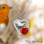 Robin on a crystal heart pendant, with a smaller red heart, hanging from a silver chain.