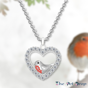 A Robin's Love Necklace. Silver heart shape with white crystals around the edge. Featuring a robin with 9 red crystals on its breast