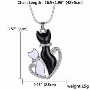bigger crystal black cat and smaller crystal white cat in a crystal heart pendant hanging from a silver chain  with dimensions.
