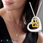 bigger crystal black cat and smaller crystal white cat in a crystal heart pendant hanging from a silver chain on a woman's neck.