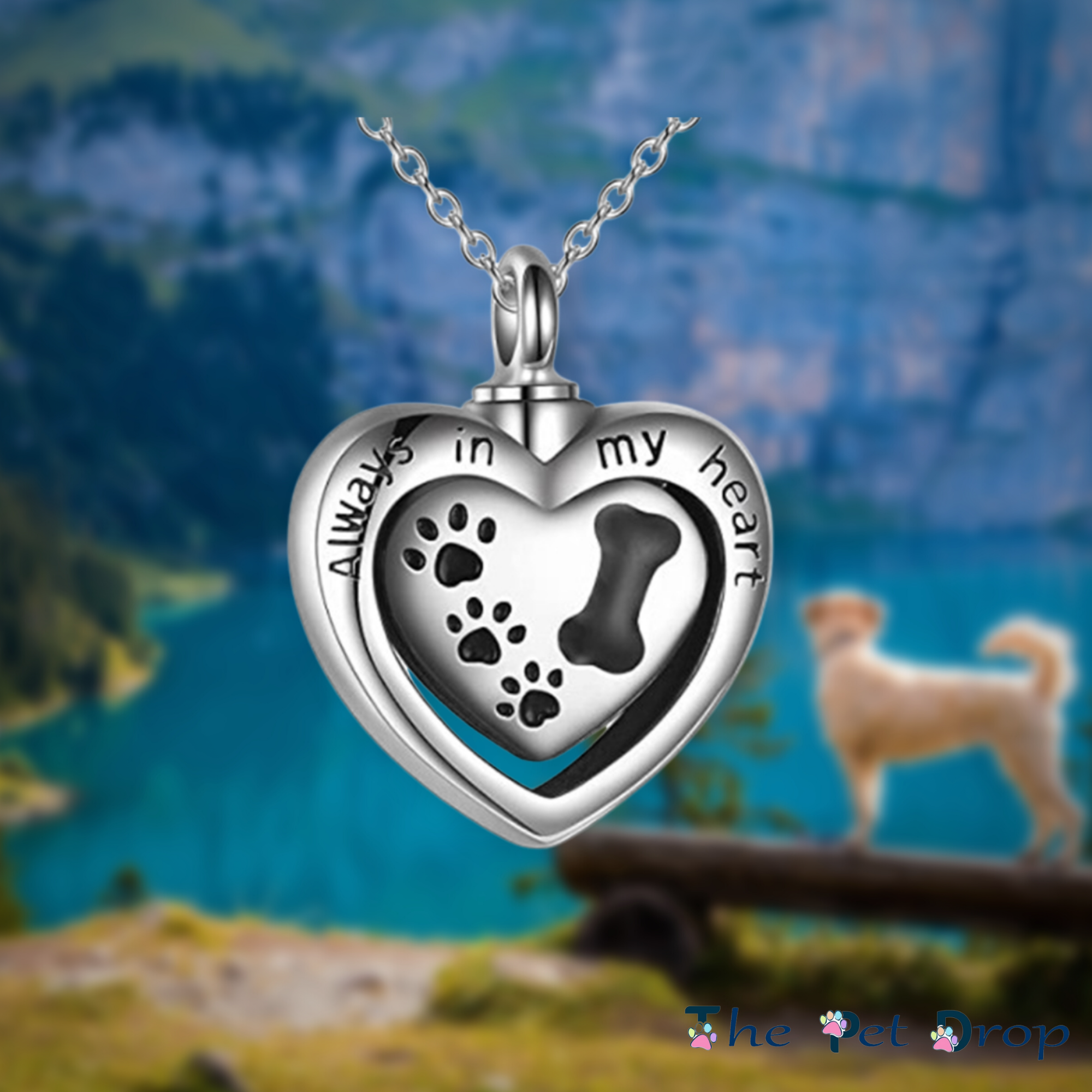 silver heart urn with black dog paw prints on it and the words "always in my heart" on the front hanging on a silver chain.