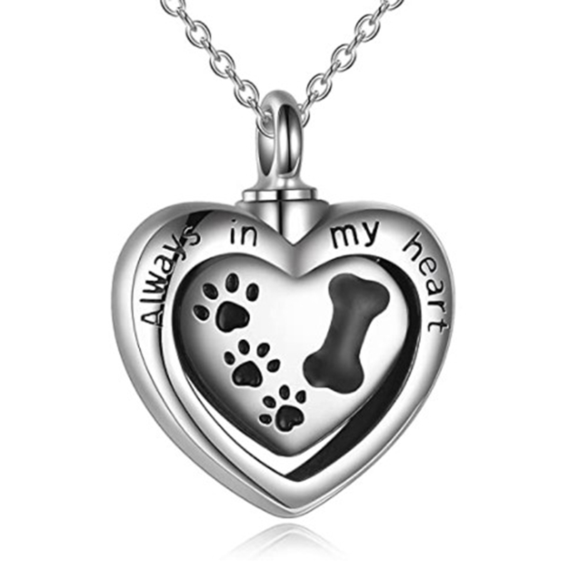silver heart urn with black dog paw prints on it and the words "always in my heart" on the front hanging on a silver chain.