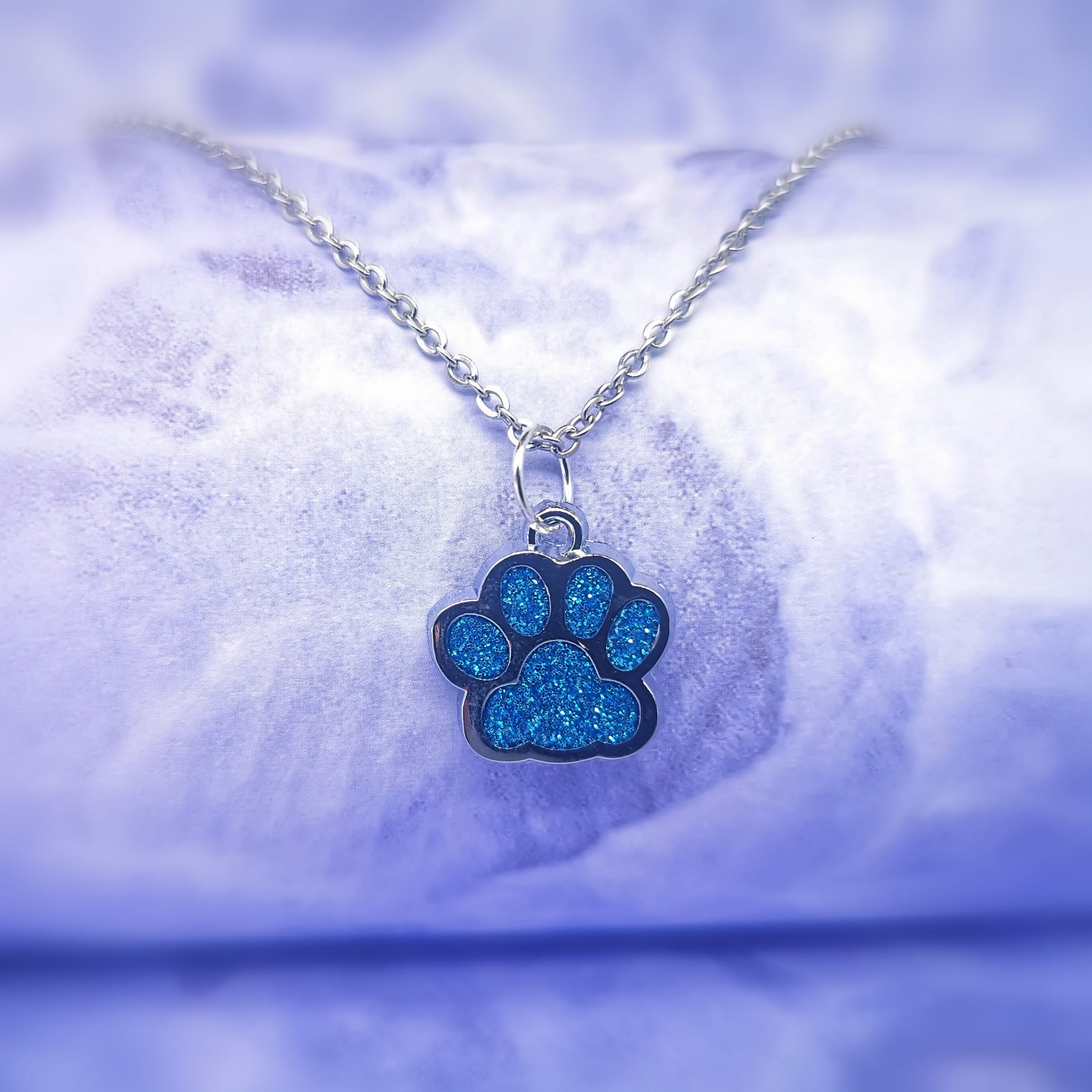 blue crystal paw print silver pendant hanging on a silver chain