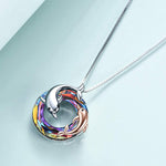 colourful crystal circle with one silver dolphin and a smaller rose gold dolphin in and around the circle pendant hanging on a silver chain.