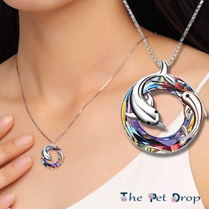 colourful crystal circle with one silver dolphin and a smaller rose gold dolphin in and around the circle pendant hanging on a silver chain on a woman's neck.