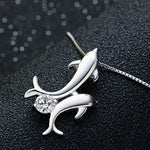 one silver dolphin with another little silver dolphin attached onto it with a clear crystal in between the two dolphins tail