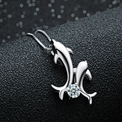 one silver dolphin with another little silver dolphin attached onto it with a clear crystal in between the two dolphins tail