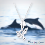 one silver dolphin with another little silver dolphin attached onto it with a clear crystal in between the two dolphins tail