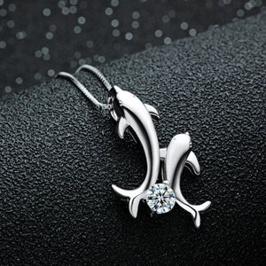 one silver dolphin with another little silver dolphin attached onto it with a clear crystal in between the two dolphins tail