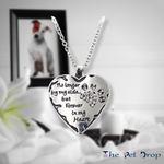 silver heart pendant with a silver crystal paw print on its side in the top corner and the words"no longer by my side... but forever in my heart" written next to the paw print hanging on a silver chain.