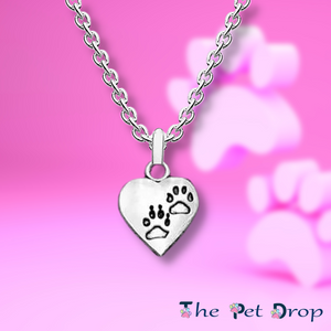 silver heart with two identical black outlined paw prints one above the other on a silver pendant hanging on a silver chain.