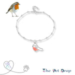 White back ground with a silver chain anklet on. The anklet has balls going around it and a lovely white and red robin hanging off the front. There is a little extension chain at the back of the anklet. 