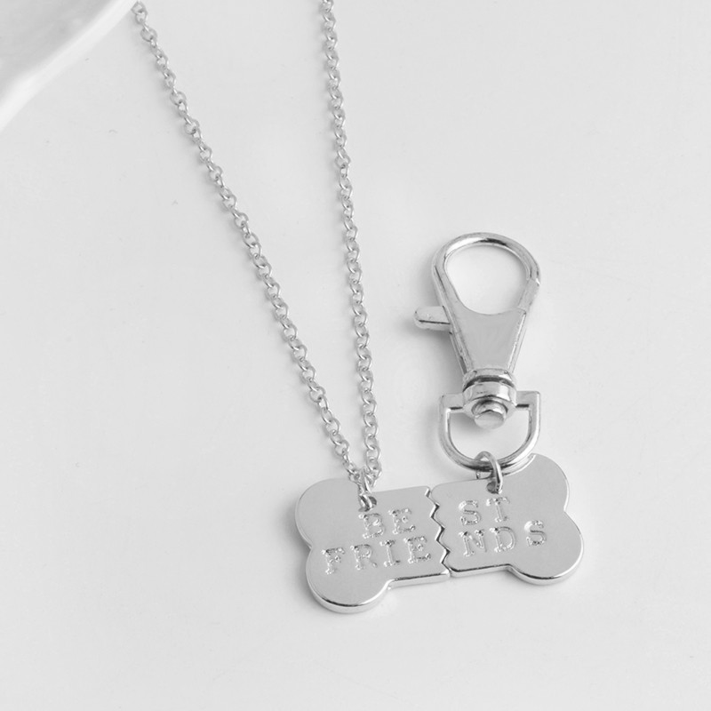 dog and human matching necklace and collar charms. silver necklace with "be" and "frie" on which matches up with the dog collar charm which says "st" and "nds". silver and in a bone shape hanging on a silver keychain hook and a silver chain.