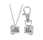 dog and human matching necklace and collar charms. silver necklace with "be" and "frie" on which matches up with the dog collar charm which says "st" and "nds". silver and in a bone shape hanging on a silver keychain hook and a silver chain.