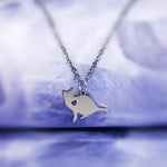 silver sitting cat pendant with a heart shaped hole in its shoulder area hanging on a silver chain.