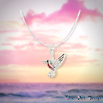 silver bird pendant with different coloured crystals hanging on a silver chain.