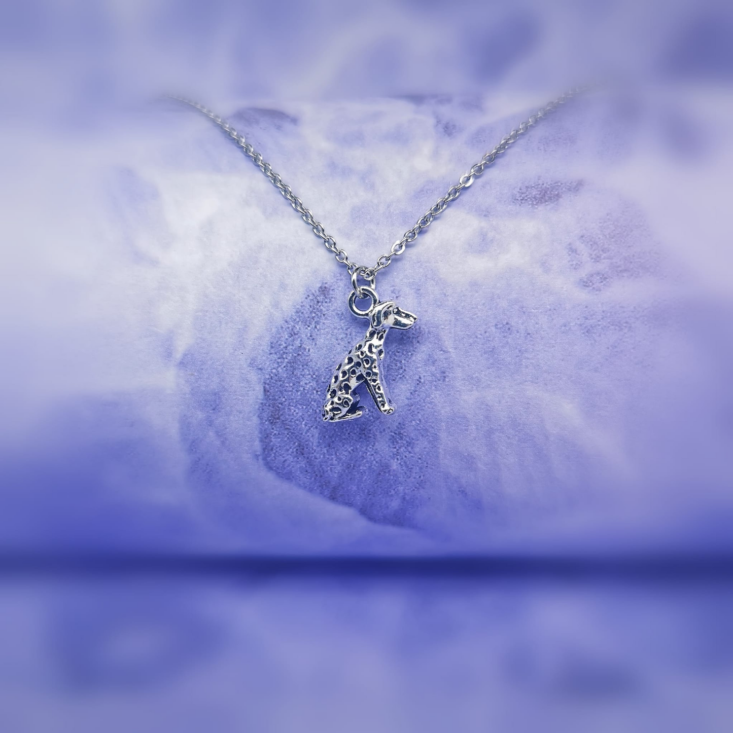sitting silver Dalmatian pendant hanging on a silver chain   
