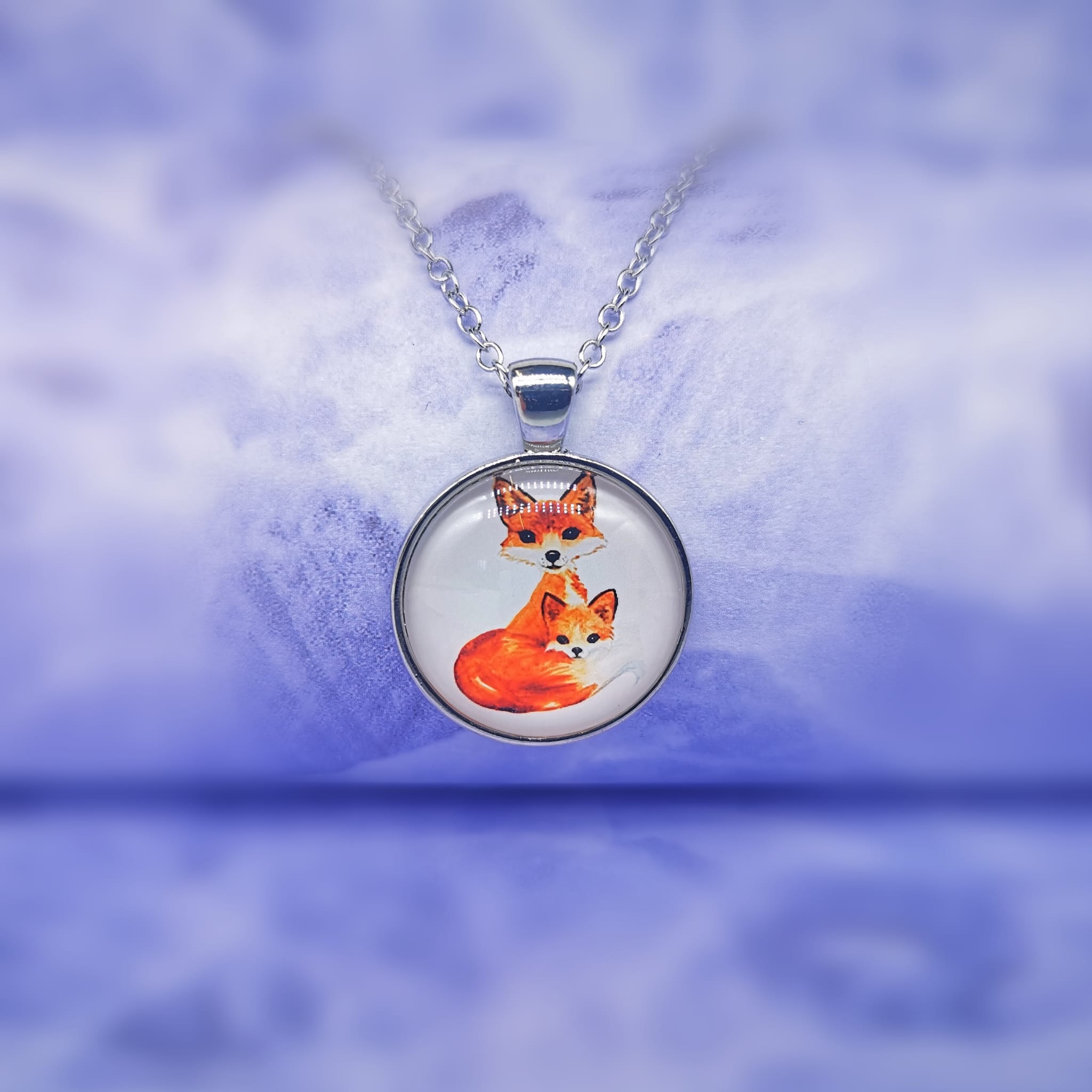 silver circle pendant with an orange fox mother and an orange fox child hanging on a silver chain